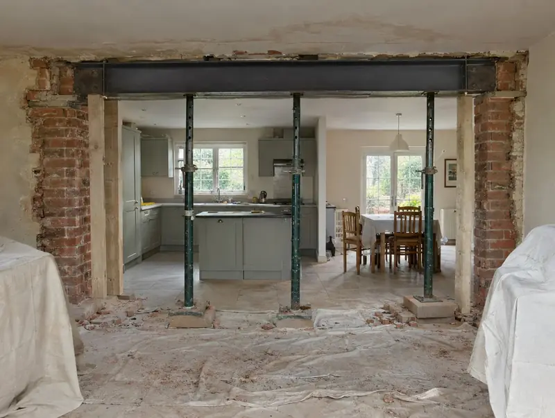 Steel beam installed across a wide opening with props in place during a knock-through